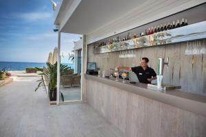 a man sitting at a bar in front of the ocean at Catalonia Royal Ses Estaques-Adults Only in Santa Eularia des Riu