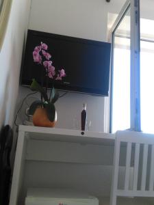 - une télévision assise au-dessus d'une table avec une fleur dans l'établissement Rooms Katica, à Korčula