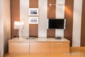 um quarto com uma cómoda com uma televisão e um candeeiro em Alcam Aribau em Barcelona