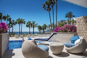 a patio with chairs and a swimming pool with palm trees at Catalonia Royal Ses Estaques-Adults Only in Santa Eularia des Riu