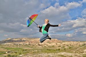 a woman jumping in the air with an umbrella at Grand Cave Suites in Göreme