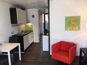 a living room with a red chair and a kitchen at Ferienwohnung SEE UND MEHR in Stetten