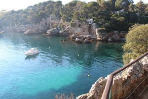 a small boat in the water next to a cliff at B&B Bessy 10 in Antibes