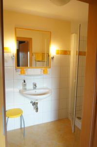 ein Badezimmer mit einem Waschbecken, einem Spiegel und einem Stuhl in der Unterkunft Pension Klimesch in Mondsee