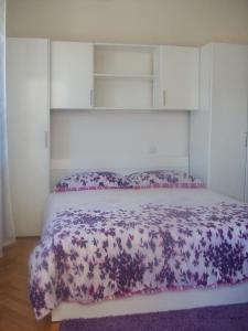 Schlafzimmer mit einem Bett mit lila und weißer Bettwäsche in der Unterkunft Studio Dominik in Makarska