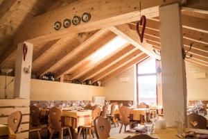 a restaurant with tables and chairs and a large window at Malga Millegrobbe Nordic Resort in Lavarone