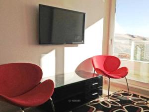 2 sillas rojas y escritorio con TV en la pared en Departamento Costa de Montemar, en Concón