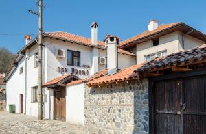 a white building with a gate and a stone wall at Къща за гости "При Примо" in Zlatograd