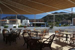 a patio with tables and chairs with mountains in the background at Antonis Hotel in Kefalos