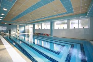 a large swimming pool with blue tiles on the ceiling at Hotel Ambra in Luhačovice