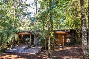 a house in the woods with a wooden deck at Huilo Huilo Nawelpi Lodge in Huilo Huilo