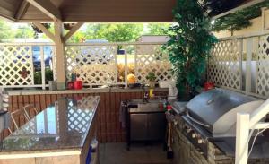 a outdoor kitchen with a grill and a sink at Inn On The Beach in Wasaga Beach