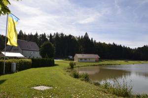 a house and a flag next to a lake at Pension Zum Grünen Wald in Feuchtwangen