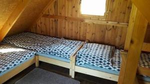 a room with two beds in a wooden cabin at Wakacyjne domki in Solina