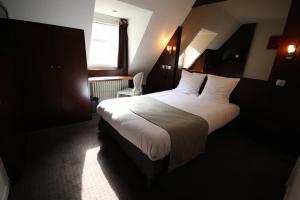 a bedroom with a bed with white sheets and a window at Hotel des Tonneliers in Strasbourg