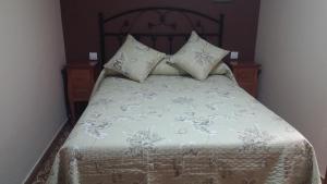 1 cama con colcha y almohadas blancas en Treselcorral en Sotres