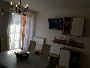 comedor con mesa, sillas y TV en Apartma Jelenček, en Moravske Toplice