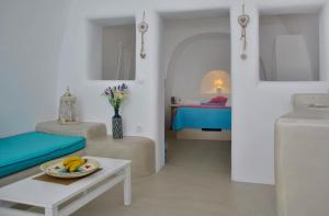 a white living room with a bed and a table at Thirea Studios in Oia