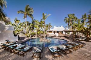 a resort pool with lounge chairs and palm trees at Hotel & Suites El Moro in La Paz