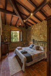 1 dormitorio con cama y pared de piedra en Casanova di Pescille, en San Gimignano