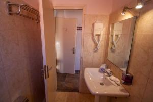 ein Bad mit einem Waschbecken, einem Spiegel und einer Dusche in der Unterkunft Ulrika in Ägina Stadt