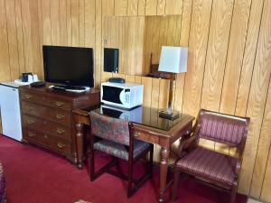 a room with a desk with a microwave and a television at Gold Pan Motel in Quesnel