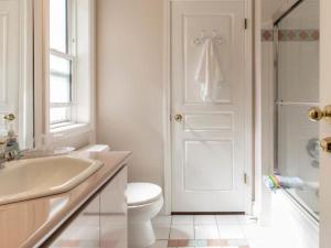 a white bathroom with a toilet and a sink at Vancouver Pacific Guest House in Richmond