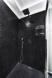 a bathroom with a shower with black tiled walls at Elea Resort - Adults Only in Oia