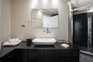 a bathroom with a large mirror and a sink at Elea Resort - Adults Only in Oia