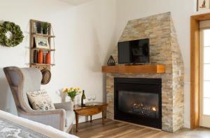 a living room with a fireplace with a tv above it at Four Chimneys Inn in Bennington
