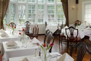 un restaurante con mesas y sillas blancas y ventanas en Four Chimneys Inn en Bennington