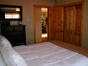 a bedroom with a large white bed and a door at Montana Style Downtown Condo in Whitefish