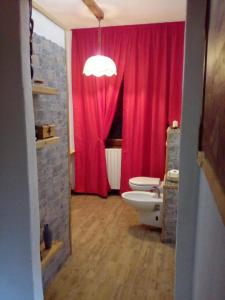 ein Badezimmer mit einem roten Vorhang und einem WC in der Unterkunft Free Hugs in Mazzo di Valtellina