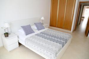 1 dormitorio con 1 cama blanca grande con almohadas moradas en Da Ponte Flats - Armacao De Pera Blue Apt., en Armação de Pêra