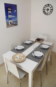 mesa de comedor blanca con sillas y reloj en Da Ponte Flats - Armacao De Pera Blue Apt., en Armação de Pêra