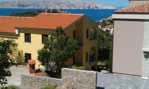 a yellow house with a stone wall next to a building at Apartments Nagj in Sveti Juraj