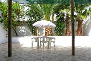 リド・マリーニにあるCasa Annaritaの傘とヤシの木が並ぶテーブルと椅子