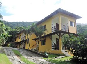 una casa amarilla con una palmera delante de ella en Pousada Portal das Estrelas, en Trindade