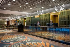 two people standing at a reception desk in a lobby at Grand Millennium Auckland in Auckland