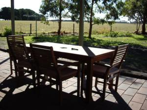 a wooden table with four chairs on a patio at Ruby Rose in Simpson