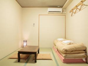 a room with a bed, chair, table and a lamp at Kyoto Hana Hostel in Kyoto