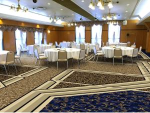 - une salle de banquet avec des tables et des chaises blanches dans l'établissement Hotel Sunroute Sano, à Sano