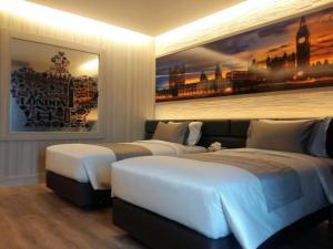 a hotel room with two beds and a painting on the wall at Maleewana Hotel & Resort in Ban Bang Muang