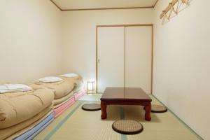 
a room with a bed, table and a lamp at Kyoto Hana Hostel in Kyoto

