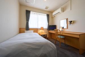 a bedroom with a bed and a desk with a computer at Towada City Hotel in Towada