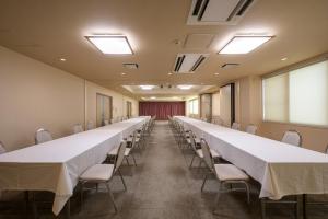 una larga fila de mesas y sillas en una habitación en Towada City Hotel en Towada