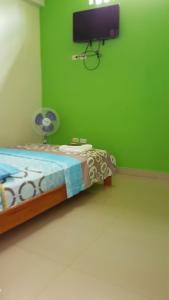 a bedroom with a bed and a tv on a green wall at Hospedaje Mas in Tarapoto