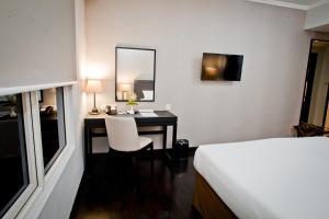 a bedroom with a desk with a bed and a mirror at Samala Hotel Jakarta Cengkareng in Jakarta