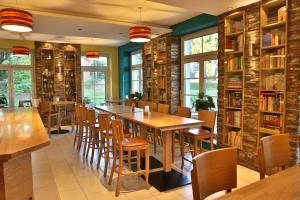 ein Restaurant mit Holztischen, Stühlen und Bücherregalen in der Unterkunft Landidyll Wilminks Parkhotel in Neuenkirchen