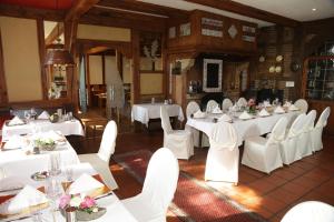 une salle à manger avec des tables et des chaises blanches dans l'établissement Landidyll Wilminks Parkhotel, à Neuenkirchen